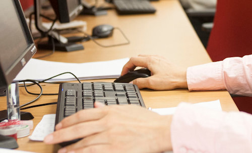 A close up of hands working on a desktop computer.